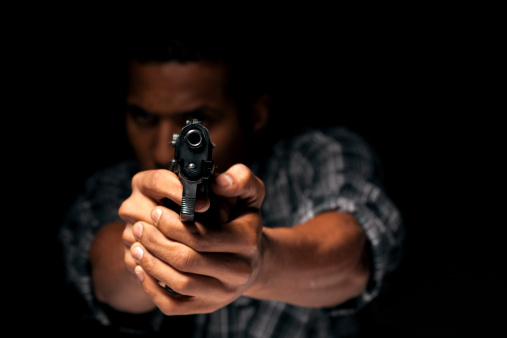 dark-skinned young man aiming with his gun at you