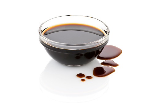 Balsamic vinegar in glass bowl with spills isolated on white backdrop.  DSRL studio photo taken with Canon EOS 5D Mk II and Canon EF 70-200mm f/2.8L IS II USM Telephoto Zoom Lens