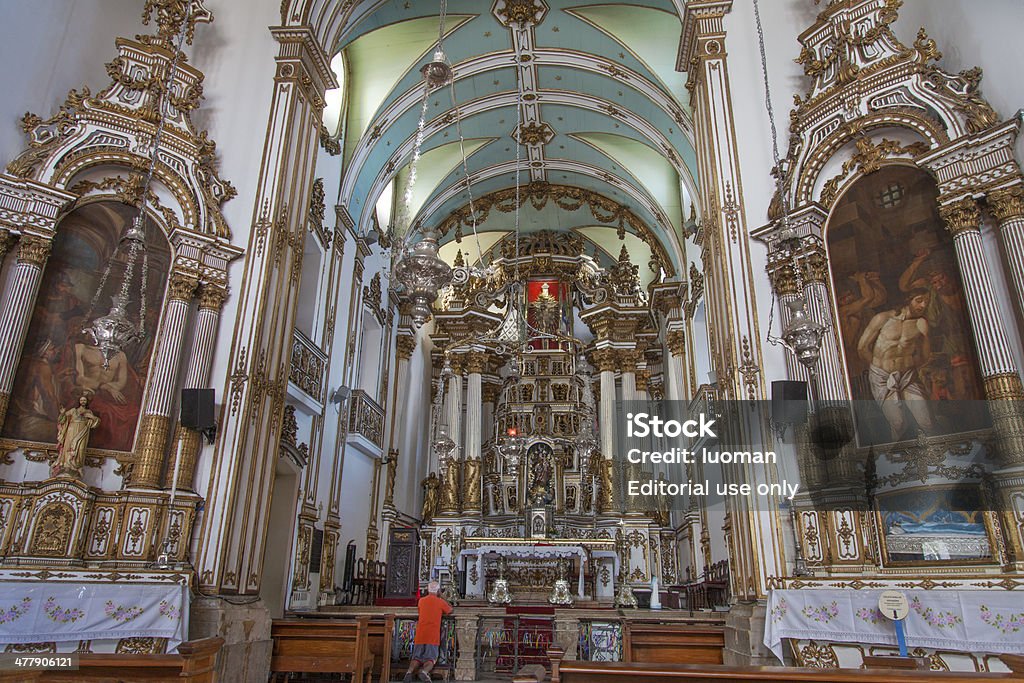 Bonfim Church in Salvador Bahia Salvador, BA, Brazil - October 3, 2012: An old man, on his knees, pray in front of the big altar of Lord Bonfim Church. The church has a lot of golden details and two paintings. The right side shows a Jesus Christ image being whipped. Adult Stock Photo