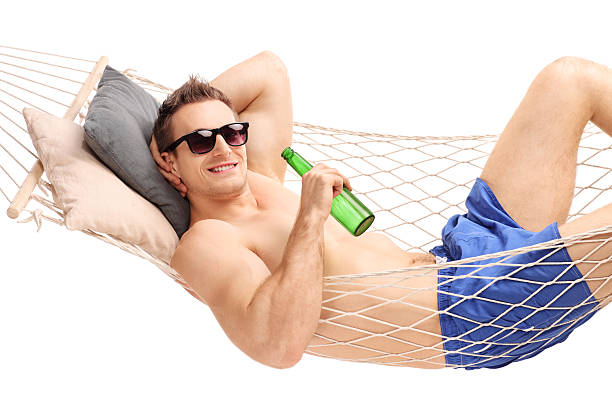 istock Relaxed man lying in a hammock and drinking a beer 477907860