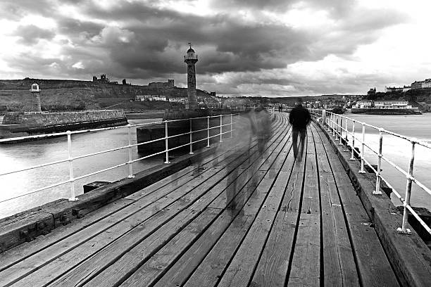 The pier at Whitby in north Yorkshire, England, after a heavy autumnal squall passes through. A partial rainbow lighting up the sea. A passenger ferry on the horizon.