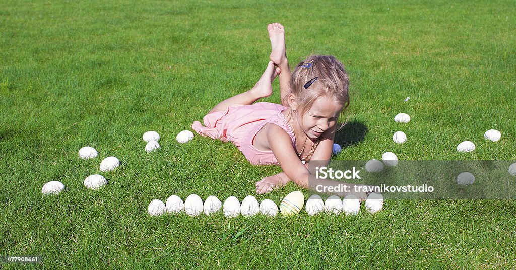 Little happy girl playing with Easter eggs on green grass Cheerful Stock Photo