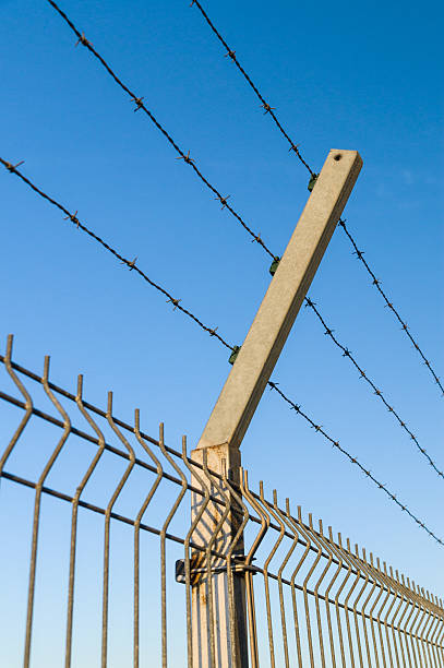 istock Security barbed wire fence against blue sky 477908750