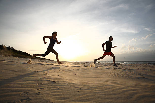 istock Man and woman running on beach at sunset 477912871