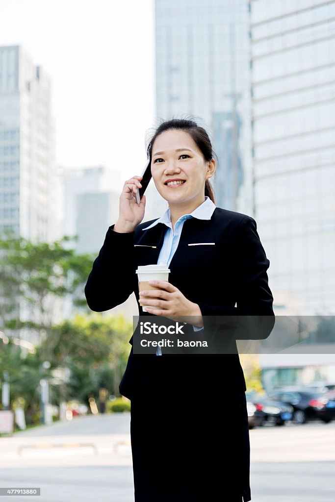 Asian businesswoman on the phone Asian businesswoman on the phone standing outside offic building. 2015 Stock Photo