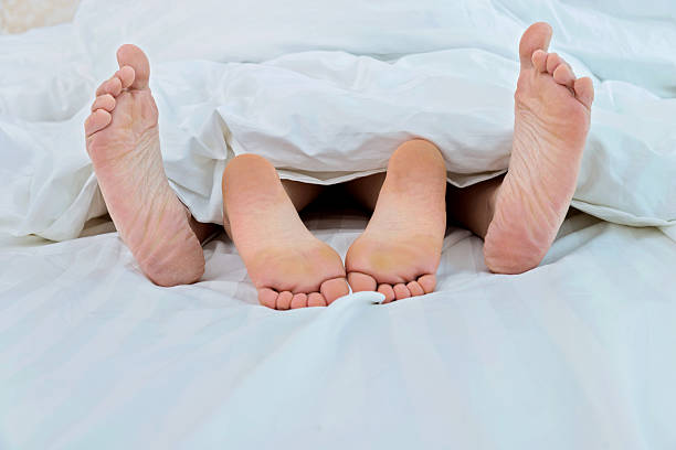 istock couple feet in bed 477920072