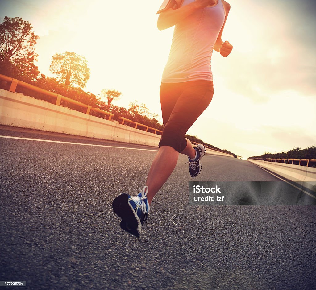 young woman runner  running on city bridge road Sunrise - Dawn Stock Photo