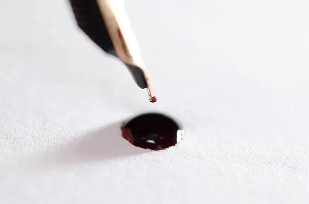 Stylograph pen with red ink drop on white paper