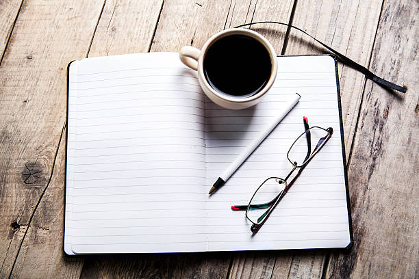 istock glasses on notebook with pen and cup of coffee 477930198