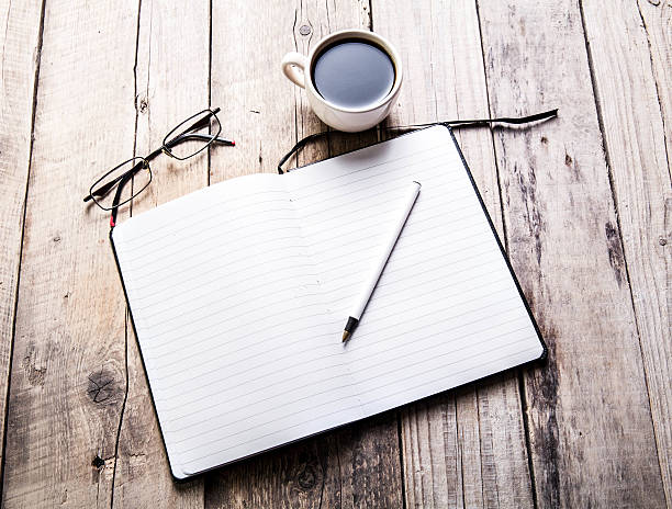 istock glasses on notebook with pen and cup of coffee 477930202