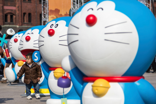 Yokohama, Japan - March 9, 2014: Unidentified child takes a photo with Doraemon figure in the 80th anniversary and new cartoon movie of Doraemon at Red Brick Warehouse, Yokohama, Japan