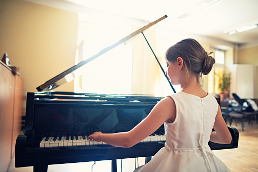 Little girl playing on grand piano