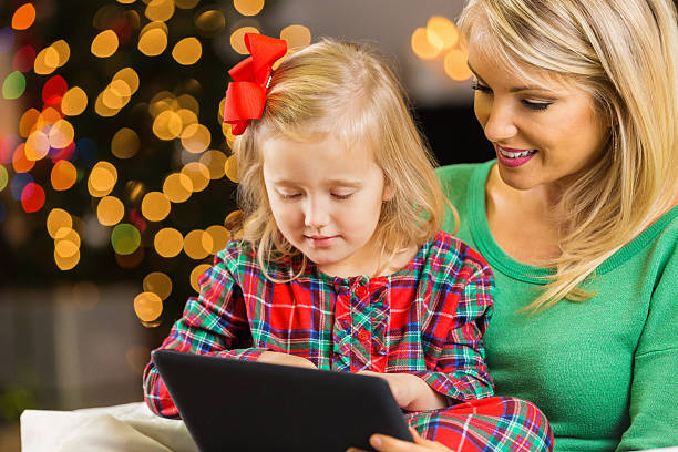 istock Mother and daughter using digital tablet together on Christmas day 477940050