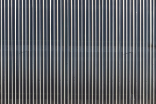 Linear geometric background or texture silvery gray color. Metal structure covered car park facade - Silver gray linear geometric background or texture. Metal structure covering car parking façade