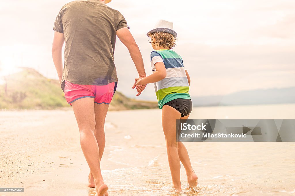 Father and son at the beach Father and son holding hands and explore the beach together 2015 Stock Photo