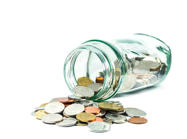 istock Coins spilling out of a glass bottle 477952908