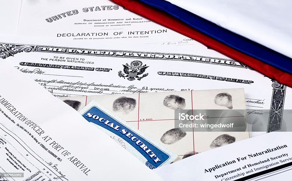 Immigration Documents US Certificate of Citizenship, declaration of intention, fingerpirnt card, social security card, application for naturalization and port of arrival manifest with red, white and blue ribbon Citizenship Stock Photo