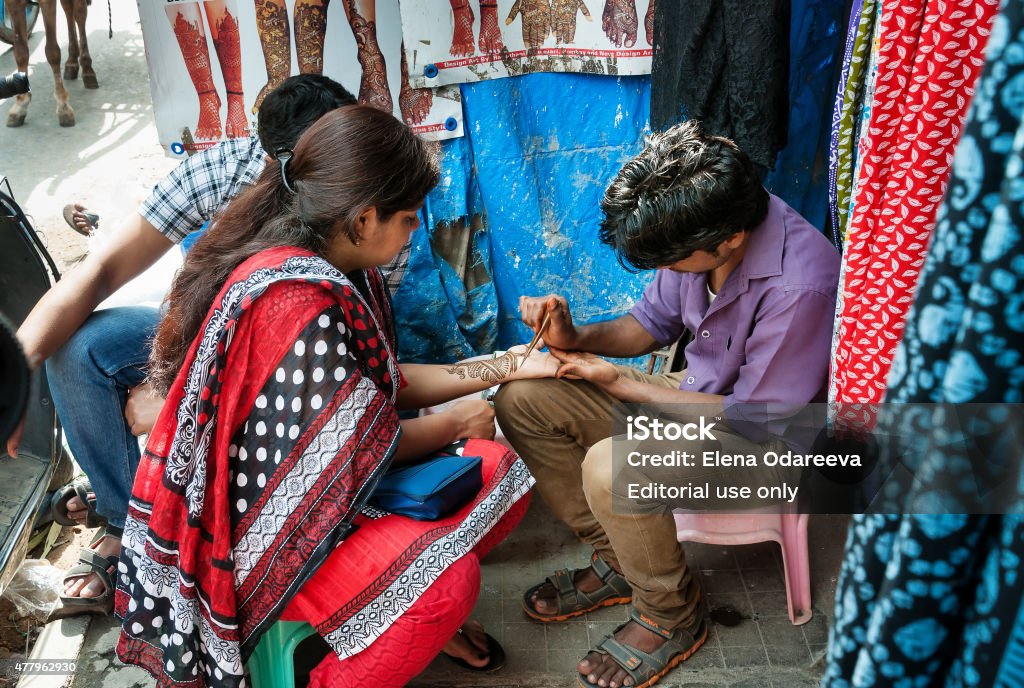 Indian man painting Henna paste on woman's hand Bangalore, India - December 25, 2014: Unidentified Indian man painting Henna paste on woman's hand at the Russell market  Russell Market is a shopping market in Bangalore, built in 1927 by the British. 2015 Stock Photo