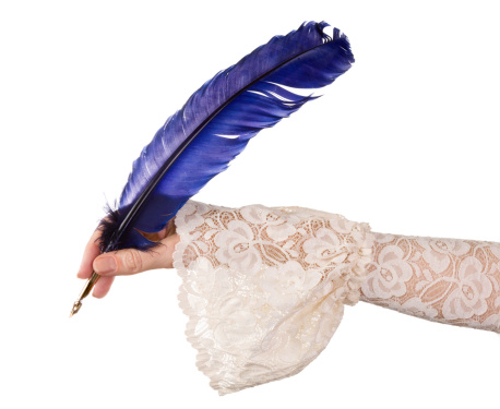 Female hand in antique sleeve writing with a quill feather