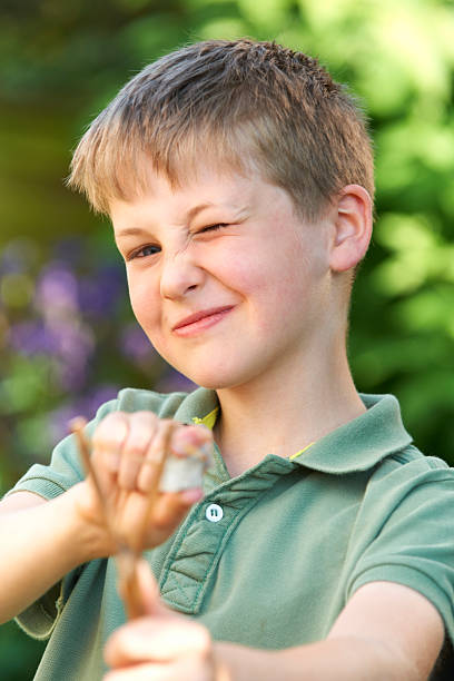 istock Boy Aiming Slingshot In Garden 477963615