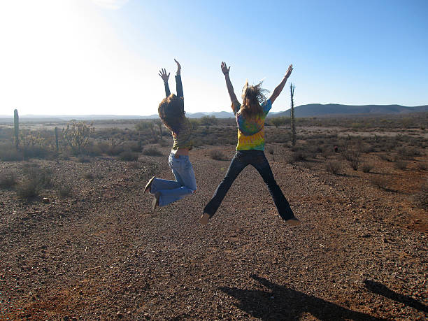 Hippie Girls Jumping in the Desert of Baja California stock photo