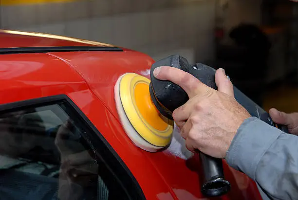 Partial view of a man holding an electric machine for polishing cars