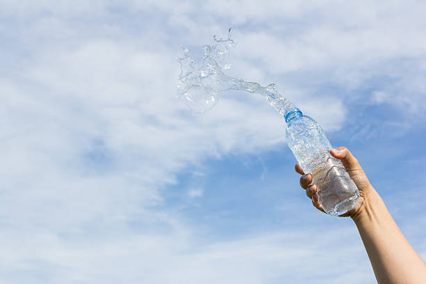 istock hand holding water bottle on sky background 477973468