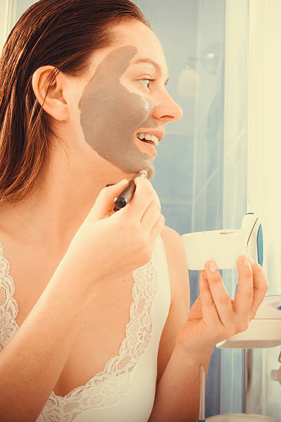 istock Woman applying mud facial mask 477978660
