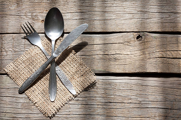 Cutlery kitchenware on old wooden boards background