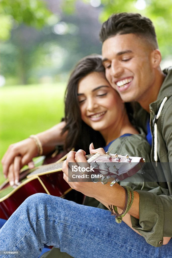 Alegre Pareja joven tocando la guitarra en el parque - Foto de stock de 20 a 29 años libre de derechos