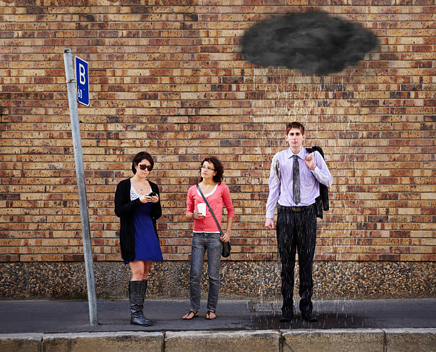 He's just got a bad feeling about today.... A black rain cloud over the young man's head standing at the bus stop soaked suit stock pictures, royalty-free photos & images