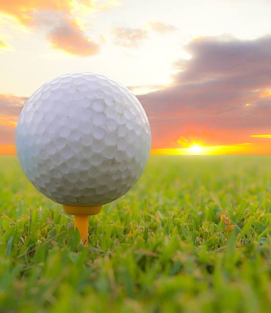 istock Golf ball on tee. Green grass, sunset 477988742