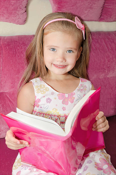 istock Little girl reading a book and siting on the sofa 477991885