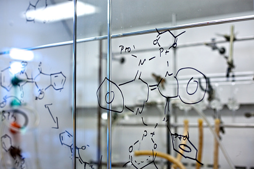 A chemical compound is scribbled on a glass wall in a chemistry lab
