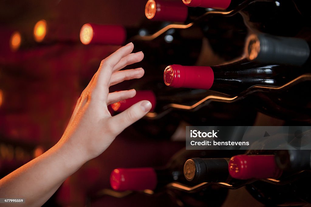 Main atteindre pour bouteille de vin dans la cave à vins - Photo de Bouteille de vin libre de droits