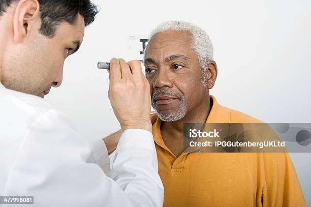Male Doctor Testing Patients Eye In Clinic Stock Photo - Download Image Now - Eye Exam, Senior Adult, Men