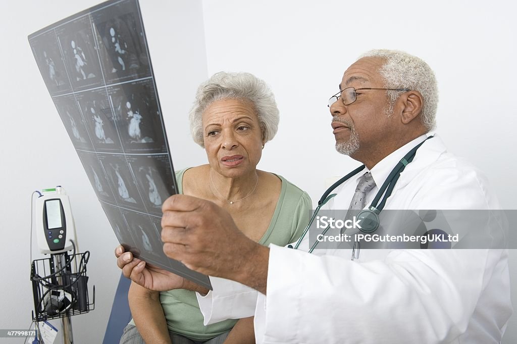 African American male doctor explaining x-ray report to patient An African American male doctor explaining x-ray report to patient at clinic Adult Stock Photo