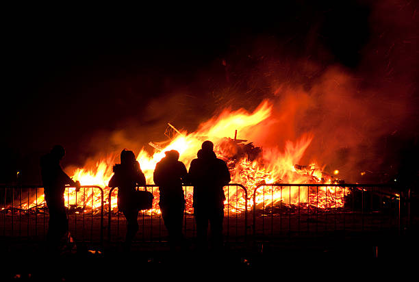 Prestwich, Greater Manchester, UK - November 5, 2013: Four people stand around the bonfire at Heaton Park, Prestwich, Greater Manchester at the bonfire night event.