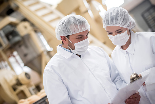 People working at a food factory doing quality control and reading documents on a clipboard