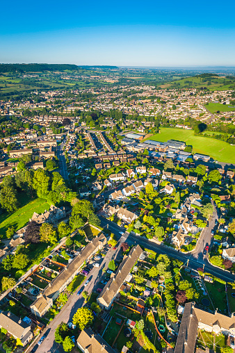 Clear blue skies over the green leafy suburban gardens and neatly kept suburban family homes of a country town surrounded by patchwork fields and rolling hills. ProPhoto RGB profile for maximum color fidelity and gamut.