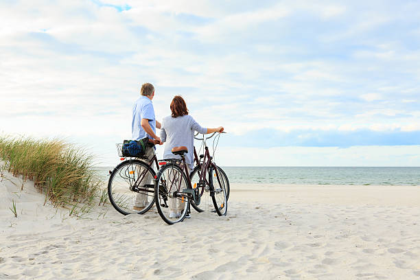 couple mature en plein air sur la plage - senior couple cycling beach bicycle photos et images de collection