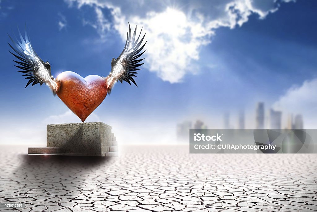 Winged heart in modern world Conceptual fine art work depicting a winged heart on a pedastal in barren landscape with city in far background Abstract Stock Photo