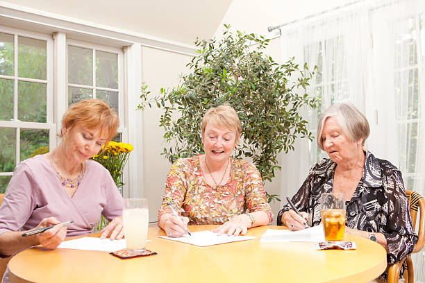 istock Senior Women Doing Paper Work Together in Social Group Gathering 478016348