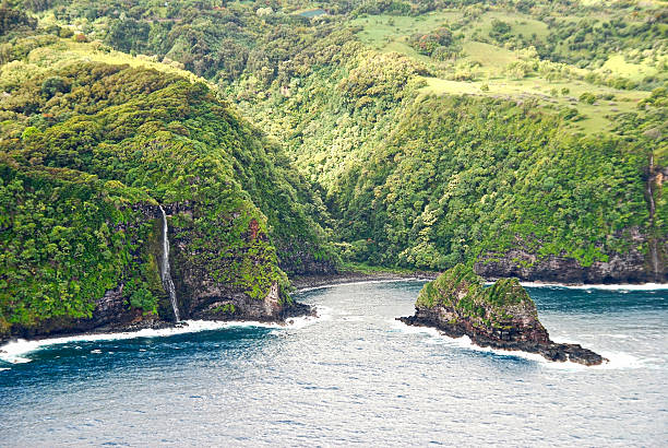 A multi-tiered waterfall, appears after a quick rain storm, flowing into a small crystal clear blue pond, inside of a dense rain-forest at side of the Road to Hana Highway, Maui, Hawaii, USA.