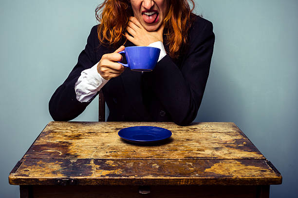 Businesswoman has had a very bad cup of coffee Businesswoman sitting at an old table is sticking her tongue out trying to erase the taste from the horrible coffee she just had gross coffee stock pictures, royalty-free photos & images