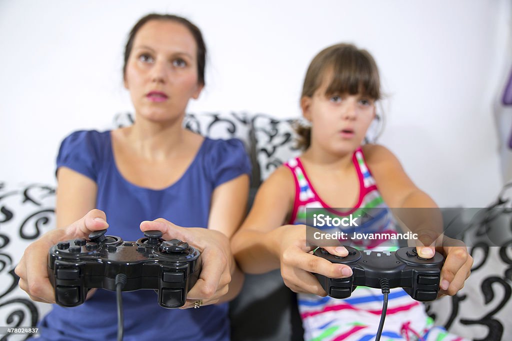 Madre e figlia che giocano a videogiochi - Foto stock royalty-free di 6-7 anni