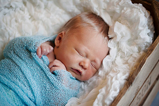 Neonato Bambino che dorme avvolto in tessuto blu - foto stock