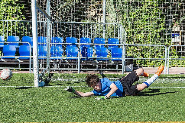 Soccer goalkeeper Young football goalkeeper stretching to stop a ball teen goalie stock pictures, royalty-free photos & images