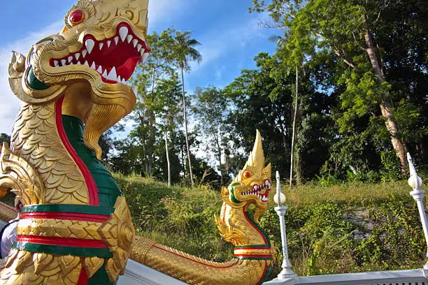 Dragon statues, adorned with gold, which are located at the bottom of the steps of a temple on the island of Ko Phi Phi in Thailand.