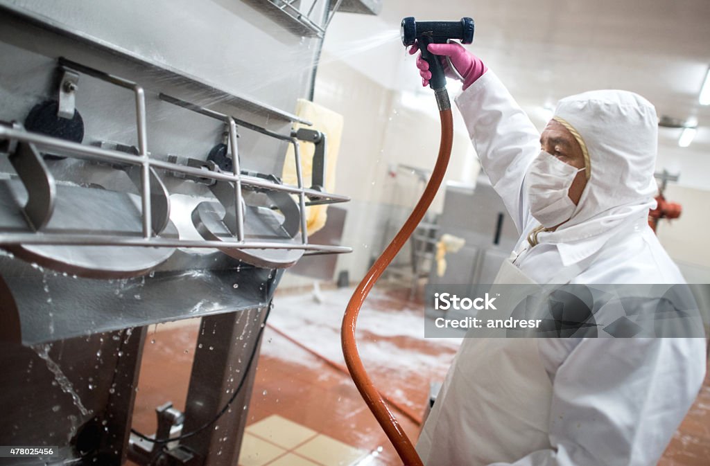 Man washing machines at a factory Man washing machines at a factory with a hose Cleaning Stock Photo